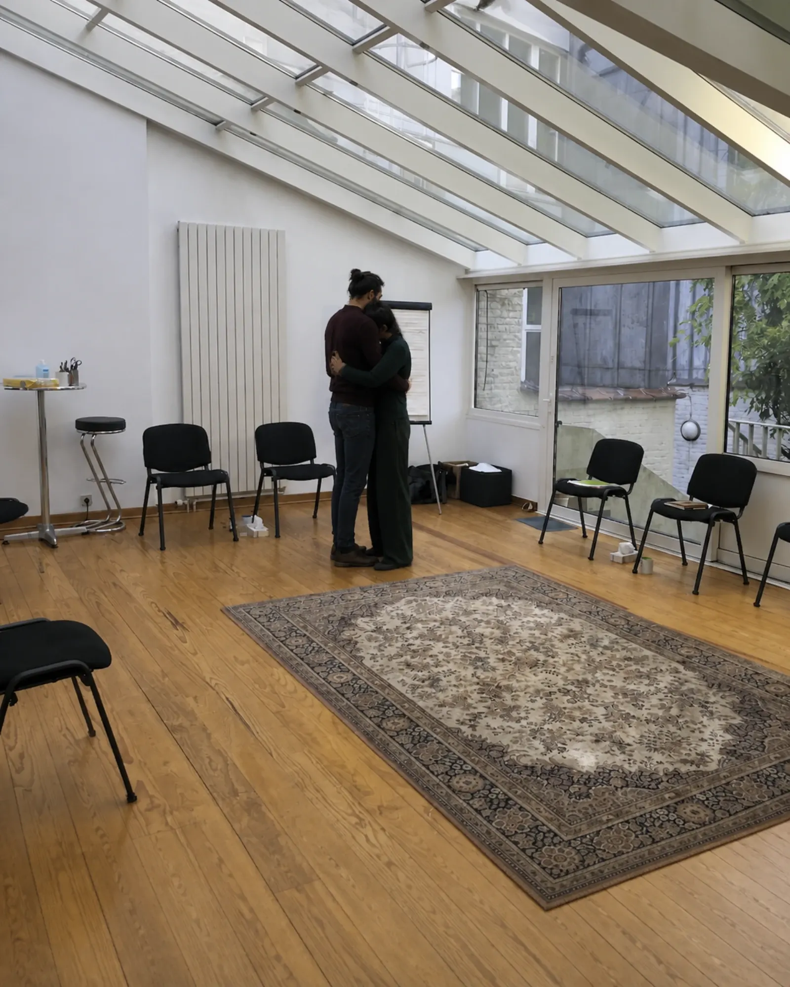Dos adultos abrazados en silencio en el porche del taller, después de algo difícil